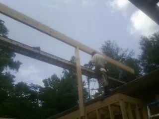 Carpenter setting a ridge beam over a new addition frame — Ice Dam Removal by Roofing Brothers in Edgerton